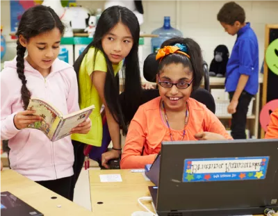 Three students in a classroom using a computer