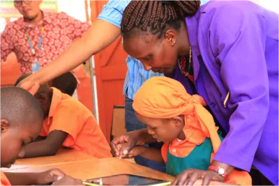 Teacher Bancy Gatimu guiding 10-year-old Tracy Wairimu on how to use the digital tablet
