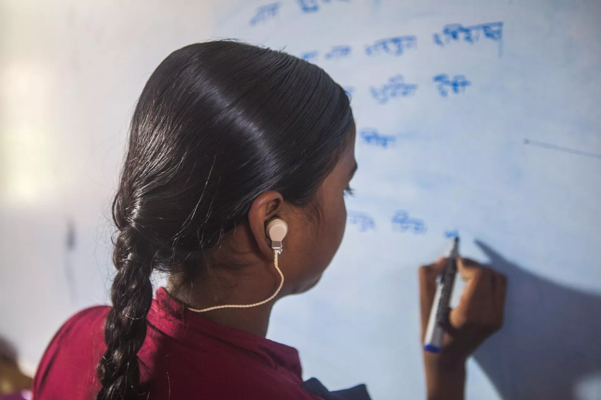 Sulekha, a girl with a hearing impairment, writes on a white board during a class at a bridge school