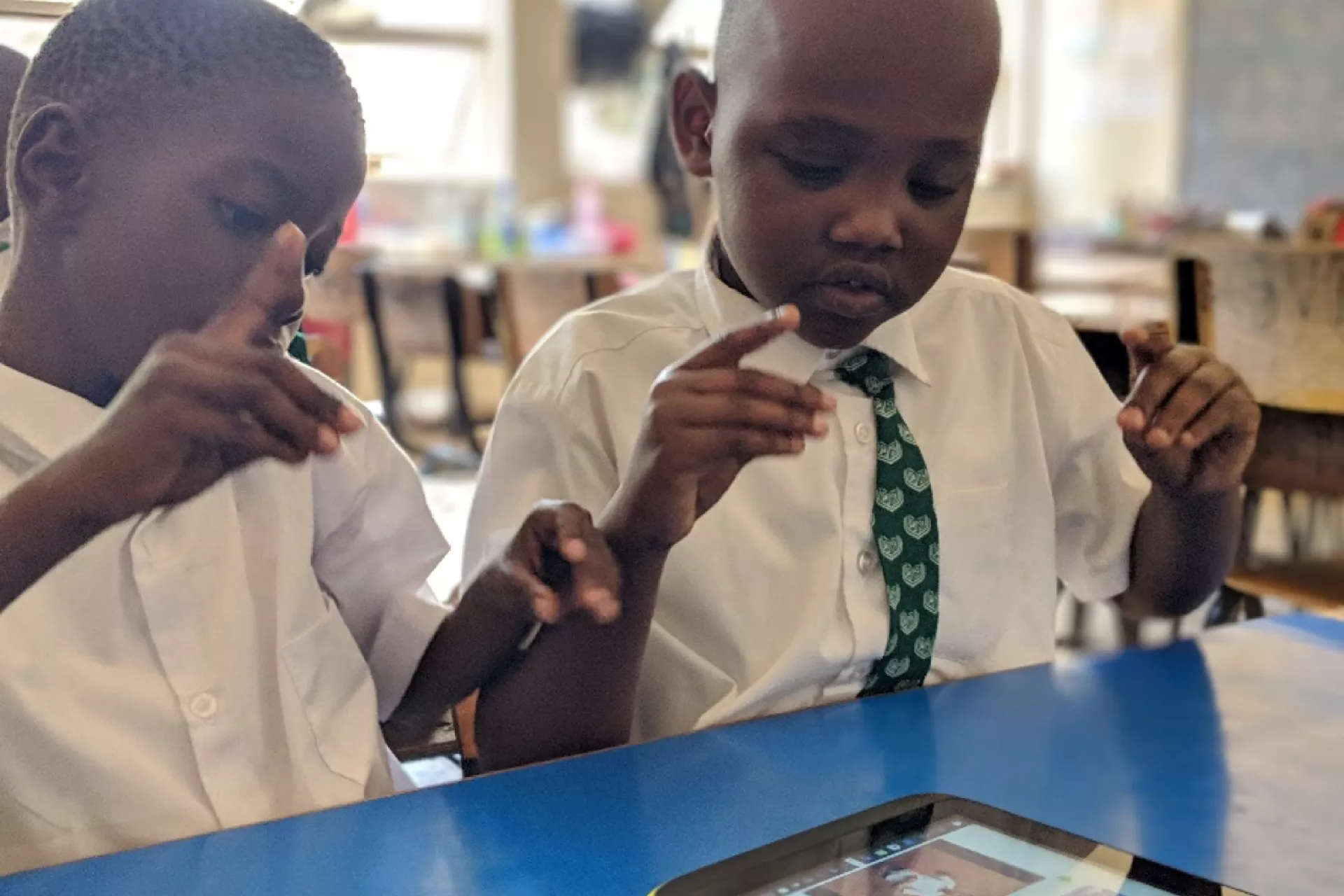 Derrick and Collins from Aga Khan Primary School signing along with the help of the interpreter in the digital accessible textbook