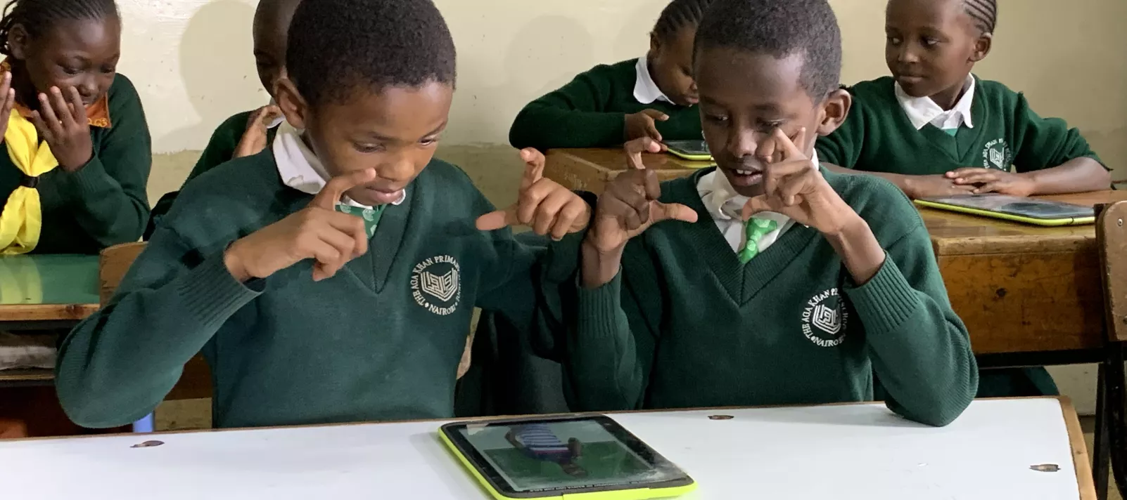 Dos niños que usan lenguaje de señas usando los libros de texto digitales accesibles en el aula