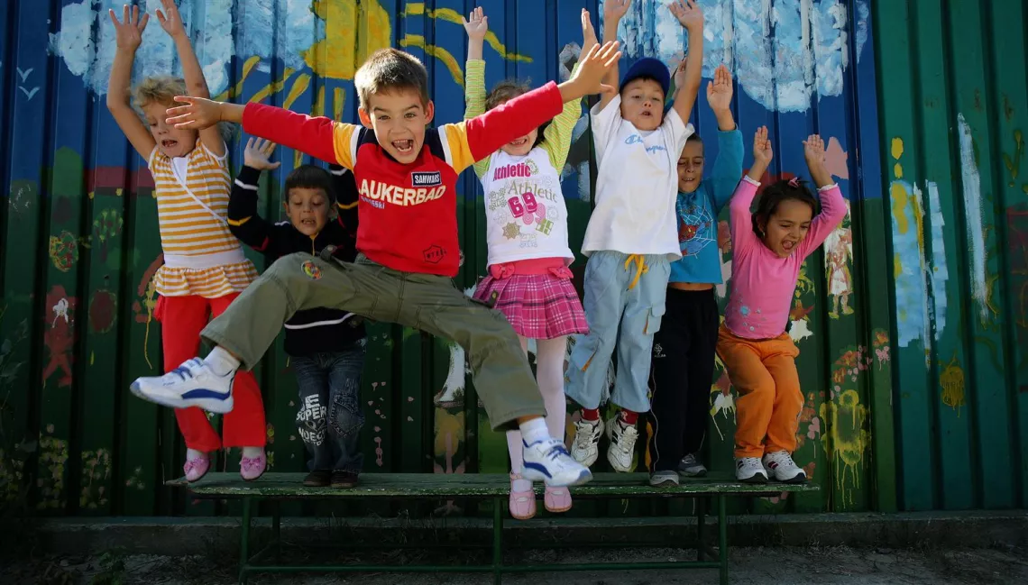 Young children jumping in a playground in Bucharest in front of a wall with graffiti